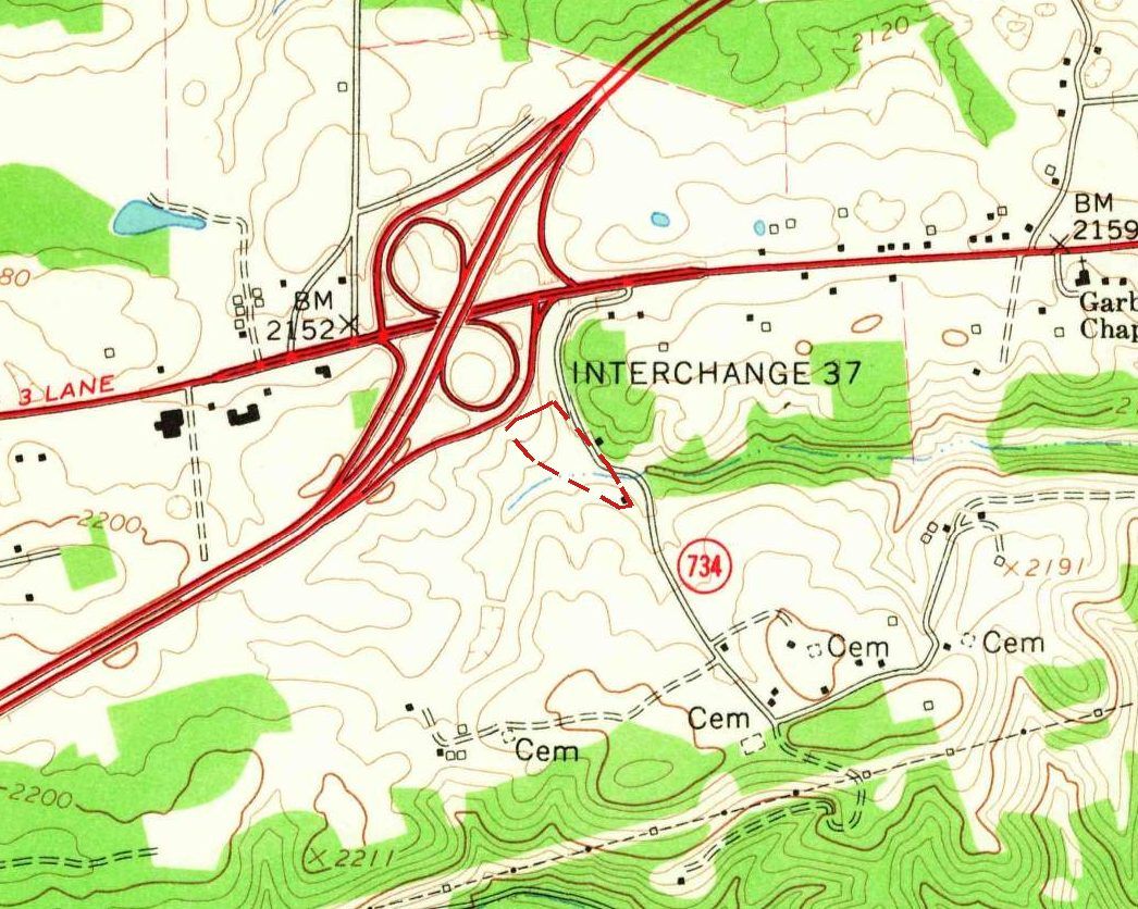 Detail of a 1965 topographic map: a red divided interstate crossing a highway marked 3 Lane in a full cloverleaf labeled Interchange 37, a small dashed red outline at the cloverleaf’s southern foot beside a road marked 734, and several places labeled Cem to the south.