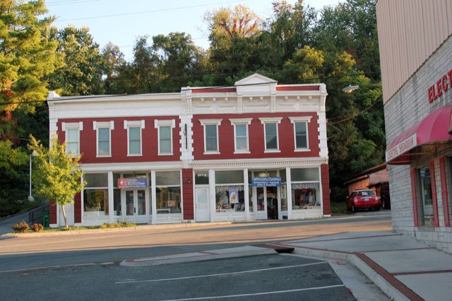 A two-story red and white brick commercial building with shop windows at the corner of Depot Street and Cambria Street